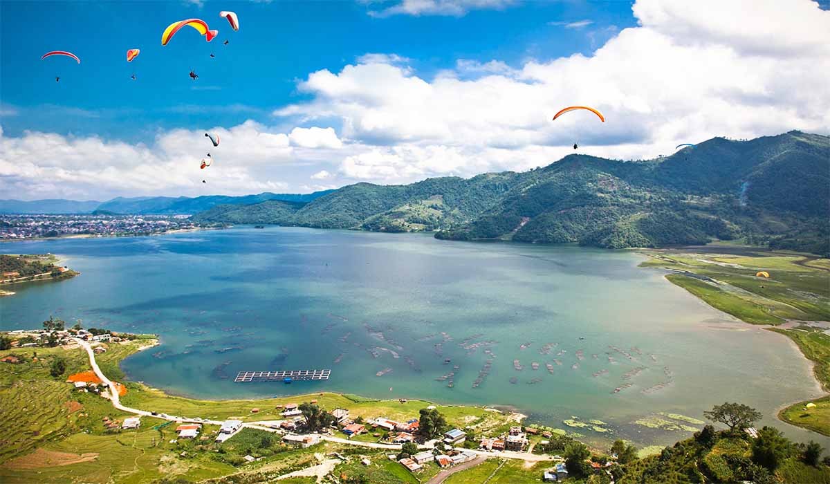 paraglider flying over the fewa lake in pokhara nepal